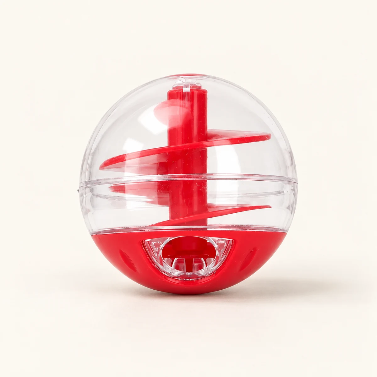 Red-and-clear spiral treat ball alone on a warm ivory surface.