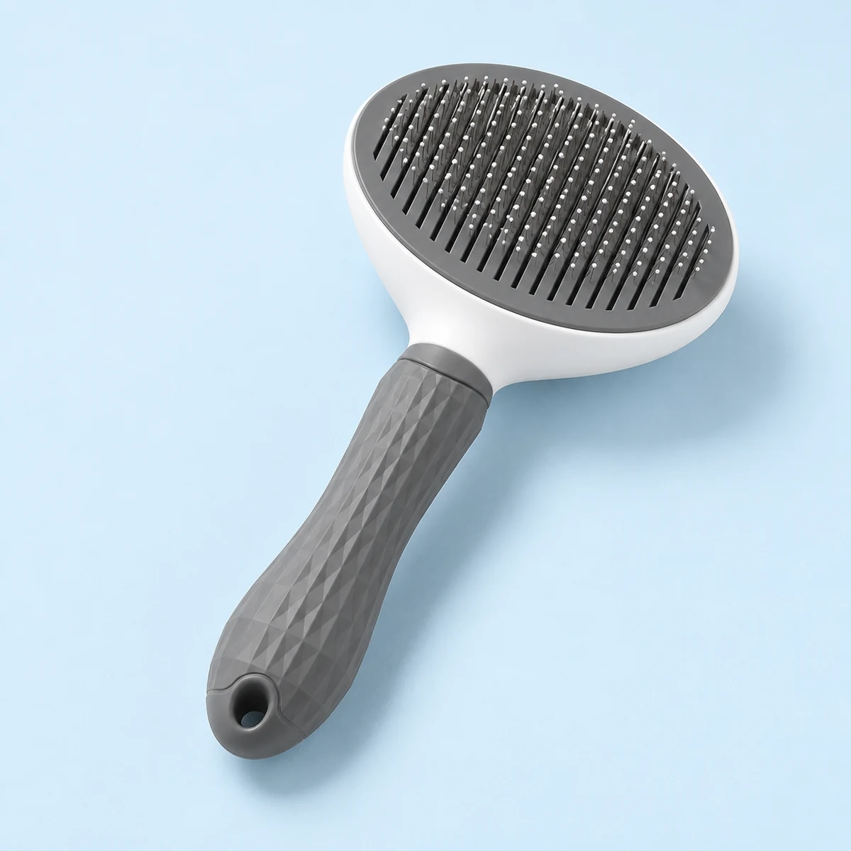 The grey-and-white oval grooming brush shown alone with its pin face visible.